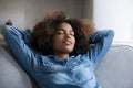 Calm sleepy teen African girl relaxing on comfortable sofa