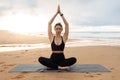 Calm slim woman practicing yoga and meditating, enjoying training on beach near sea, exercising outdoors, free space Royalty Free Stock Photo