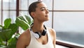Calm smiling millennial latin lady in sportswear and wireless headphones, enjoy rest