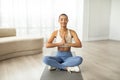 Calm smiling slim millennial latin lady in sportswear practice yoga in lotus position with closes eyes