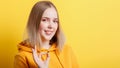 Calm smiling teenage blonde girl shows positive ok gesture symbol like and approval isolated on color yellow background. Portrait Royalty Free Stock Photo