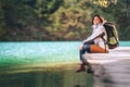 Calm smiling woman traveler sits on wood bridge near the mountain lake at sunny autumn day Royalty Free Stock Photo