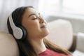 Calm Smiling Young Asian Woman In Wireless Headphones Listening Music At Home Royalty Free Stock Photo