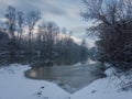 Calm snowy winter scene with river, snow covered riverbanks and naked trees Royalty Free Stock Photo