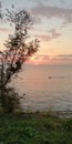 Calm stately natural background. Boat on the sea surface against the backdrop of the sunset landscape in pink and purple tones.