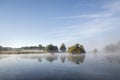 Calm still lake with mist hanging over water on frosty Autumn Fa