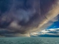 calm before the storm, a storm cloud is coming, covering the bright sky and partially visible rainbow Royalty Free Stock Photo