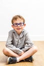 Calm studious child with eyeglasses and a missing tooth sitting Royalty Free Stock Photo