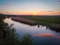 The calm surface of the river and the reflections of clouds, orange sunset, green fields and meadows in a quiet warm summer evenin Royalty Free Stock Photo