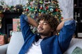 Calm and tired young Indian man in blue shirt resting on sofa at home on New Year holidays. Closing his eyes, throwing Royalty Free Stock Photo