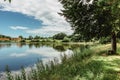 A calm and tranquil zen-like sunny day by a lake with reflections on the water.Park with green grass and trees.Tranquil Background Royalty Free Stock Photo