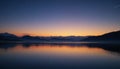 Calm twilight scene with a serene lake reflecting the fading light of dusk. The sky
