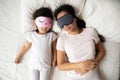 Calm Vietnamese mother and small daughter daydream in bed