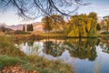 Calm water of garden pond at sunset reflecting surrounding trees, grasses, and mountains. Royalty Free Stock Photo