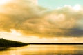 Calm water landscape. View of the pond, lake. Beautiful orange sky. Orange sky and a huge cloud reflected in the water