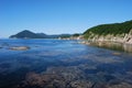 Calm waters of a bay. Rocky seashore of a Pacific Ocean. Saltwater inlet. Green hills by the sea. Rocks on the shallows. Royalty Free Stock Photo