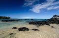 Calm waters behind black basalt rocks at Puako beach