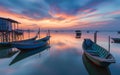 Calm waters reflect a sublime sunset at a peaceful fishing village, with traditional boats moored beside rustic stilt Royalty Free Stock Photo