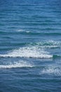 Calm waves in the empty ocean on a sunny day. Beautiful sea water with light ripple effects on the surface. Abstract