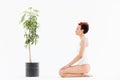 Calm woman with eyes closed sitting near tree in pot Royalty Free Stock Photo