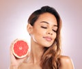 Calm woman, grapefruit and vitamin C for skincare or beauty against a studio background. Face of female person or model