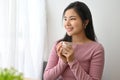 Calm young Asian woman sipping a coffee while looking out the window Royalty Free Stock Photo