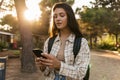 Calm young caucasian girl chatting using smartphone on street sunny day. Royalty Free Stock Photo