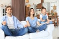 Calm young family with little daughter sit on couch practice yoga together, happy parents with small preschooler girl