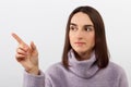 Calm young girl points her finger to the side on a white background. look away. Royalty Free Stock Photo