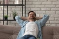 Calm young man relax on sofa at home sleeping