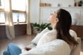 Calm young woman relax on sofa breathing fresh air