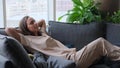 A calm young woman is resting on a couch with her eyes closed, her hands behind her head. A beautiful woman is Royalty Free Stock Photo