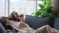 A calm young woman is resting on a couch with her eyes closed, her hands behind her head. A beautiful woman is Royalty Free Stock Photo