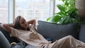 A calm young woman is resting on a couch with her eyes closed, her hands behind her head. A beautiful woman is Royalty Free Stock Photo