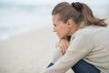 Calm young woman sitting on cold beach Royalty Free Stock Photo