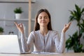 Calm young woman taking break doing yoga exercise at workplace