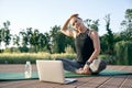 Calm your mind. Athletic beautiful middle aged woman watching instructional videos on a laptop while exercising on a mat Royalty Free Stock Photo