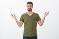 Calming down and releasing stress with meditation. Determined and relaxed attractive bearded guy in olive t-shirt