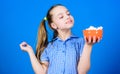 Calorie and diet. Girl smiling face hold bowl sweets marshmallows in hand blue background. Kid girl with long hair like