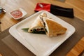 Calzone pizza halves on bamboo sheet in square plate on wooden table