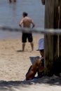 Person on the beach doing crossword puzzles in the shade. Arembepe Beach, Camacari, Bahia, Brazil