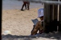Person on the beach doing crossword puzzles in the shade. Arembepe Beach, Camacari, Bahia, Brazil