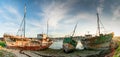 Panorama view of old fishing boat wrecks stranded on a rocky beach at sunset