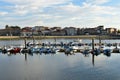 Small fishing village with pier and boats. Beach, harbour and promenade with trees. Sunset light, blue sky with clouds. Cambados,