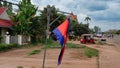 Cambodia flag swaying in the wind, street of an Asian city, red tuktuk