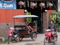 Little Asian girl plays in a motor rickshaw, a scooter rides along the road