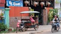 Little Asian girl plays in a motor rickshaw, a scooter rides along the road