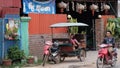 Little Asian girl plays in a motor rickshaw, a scooter rides along the road