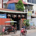 A little Asian girl plays in a motor rickshaw, a scooter rides along the road