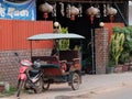 Little Asian girl sits in a moto rickshaw near a house with red lanterns